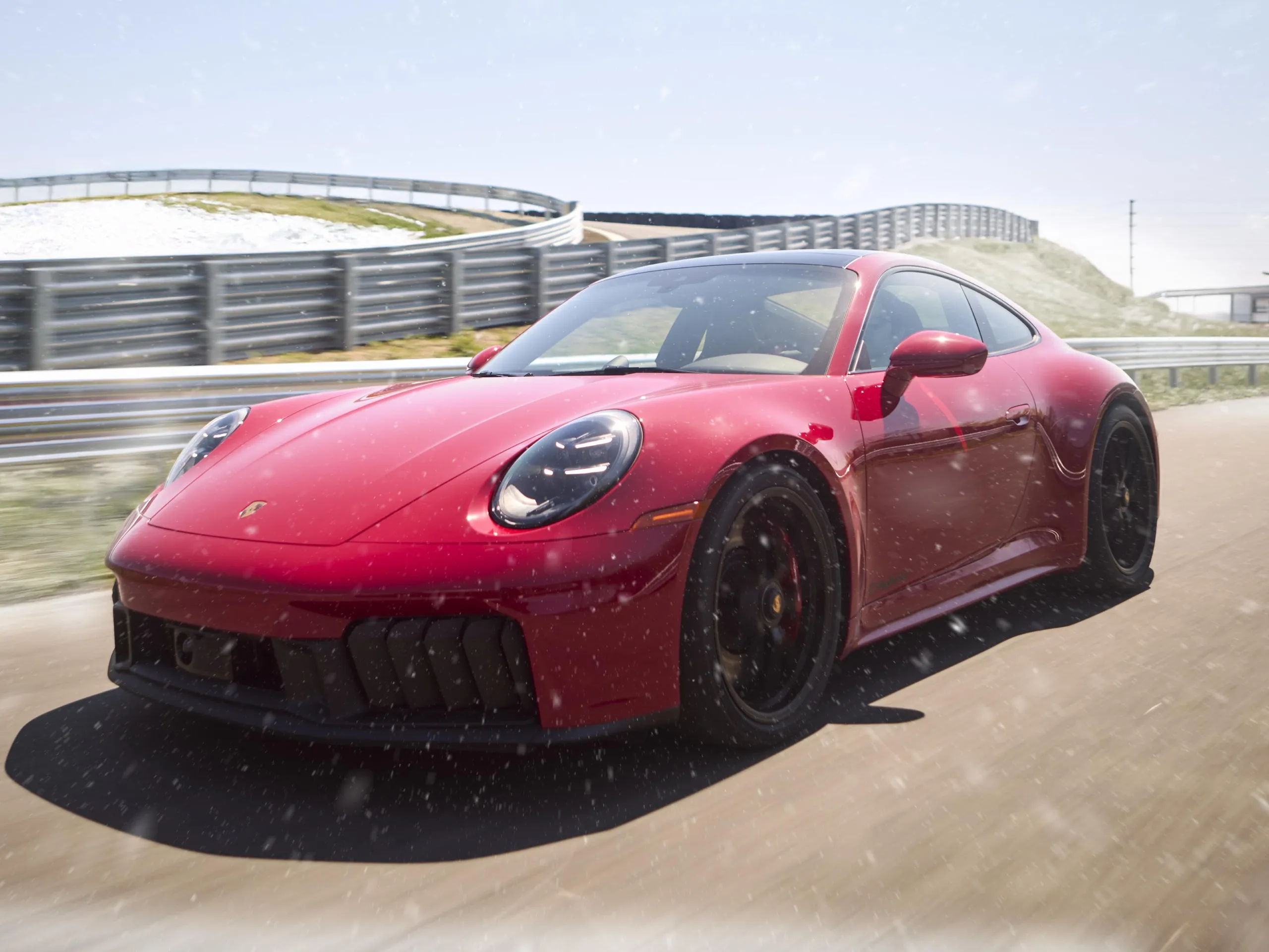 A red Porsche 911 driving down a straightaway on a snowy circuit.