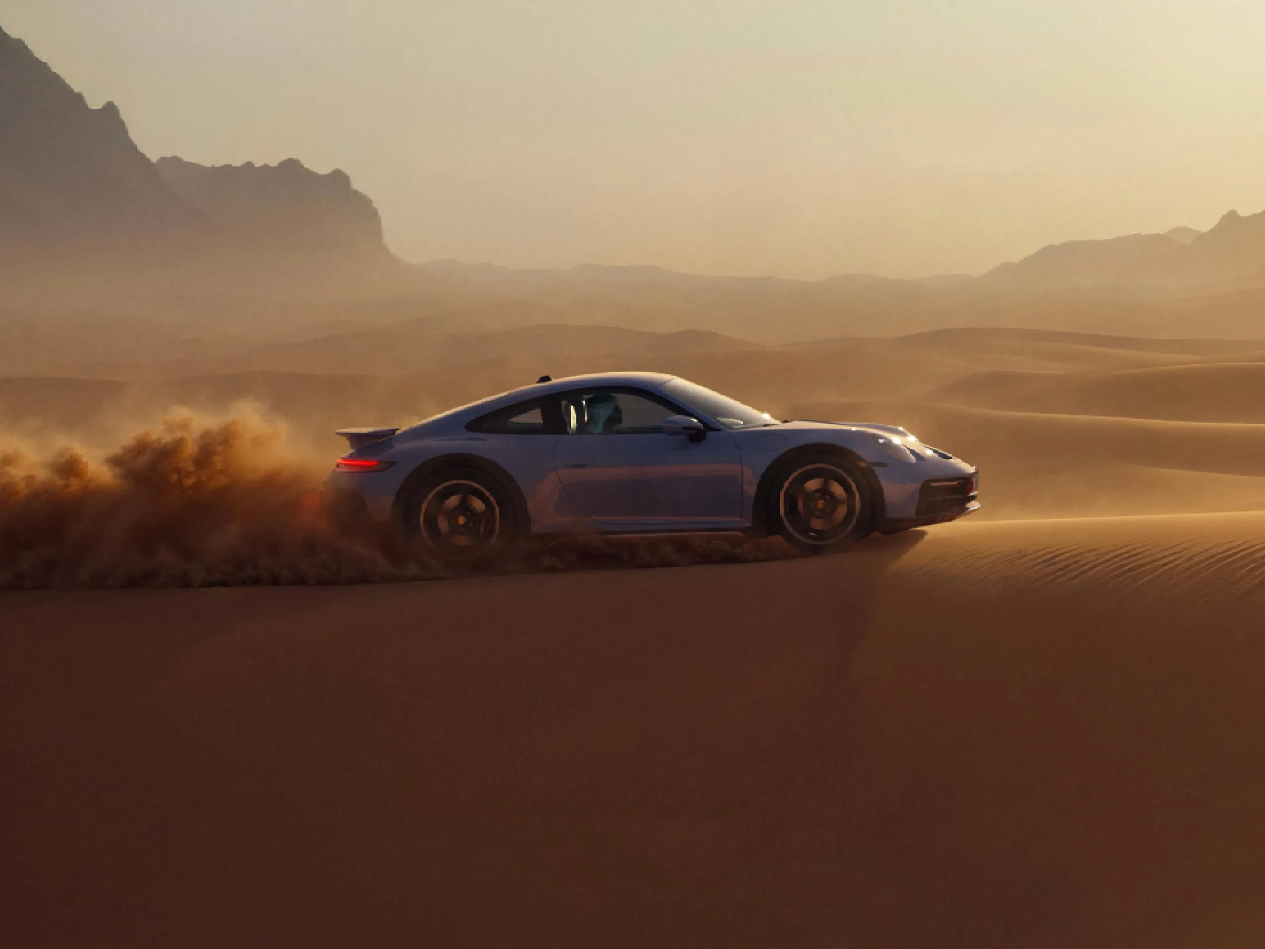 Porsche 911 Dakar by Sonderwunsch speeds across desert sand dunes.
