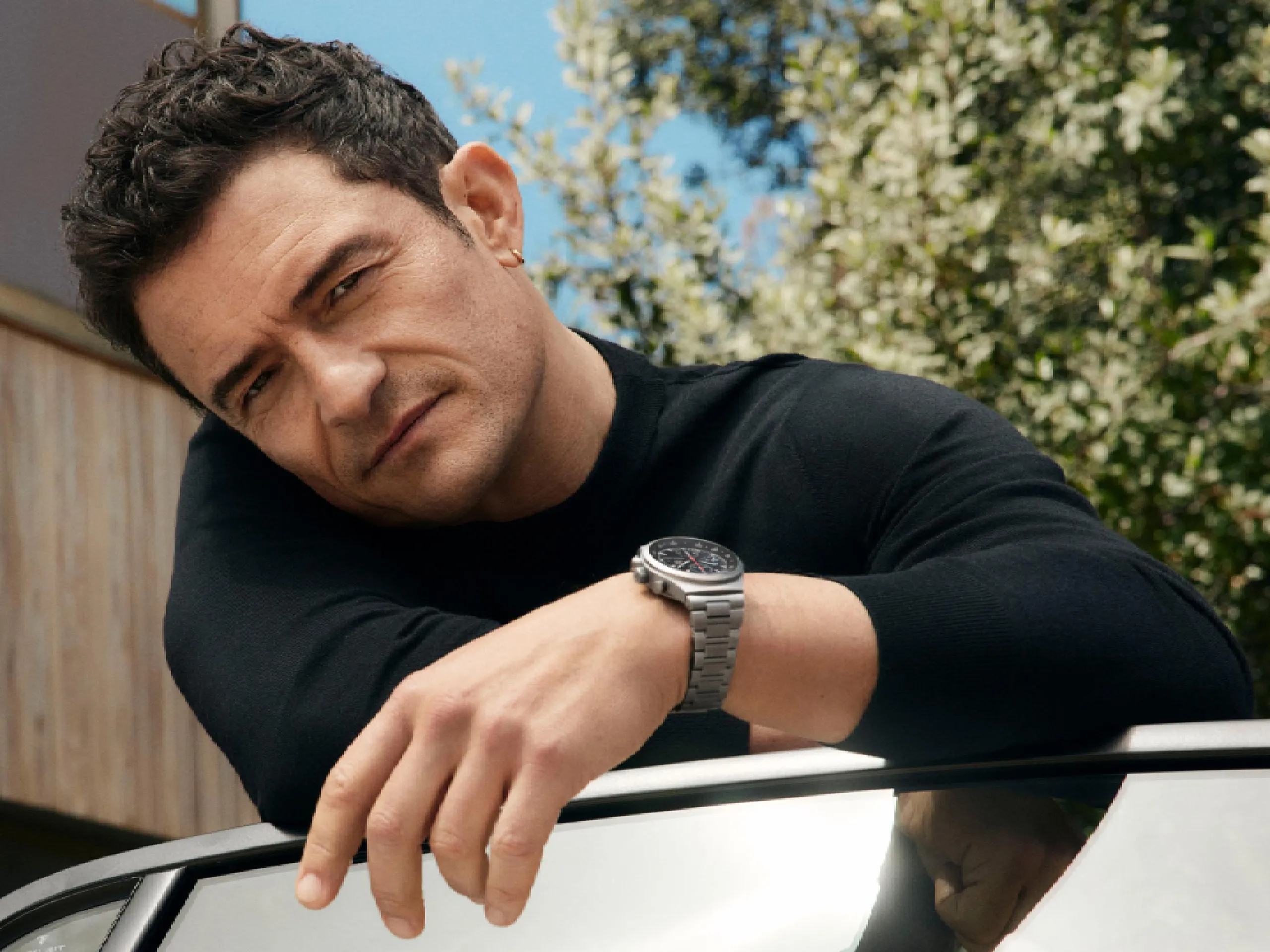 Orlando Bloom leans over an open car door wearing the Chronograph 1 – 1975 Limited Edition.
