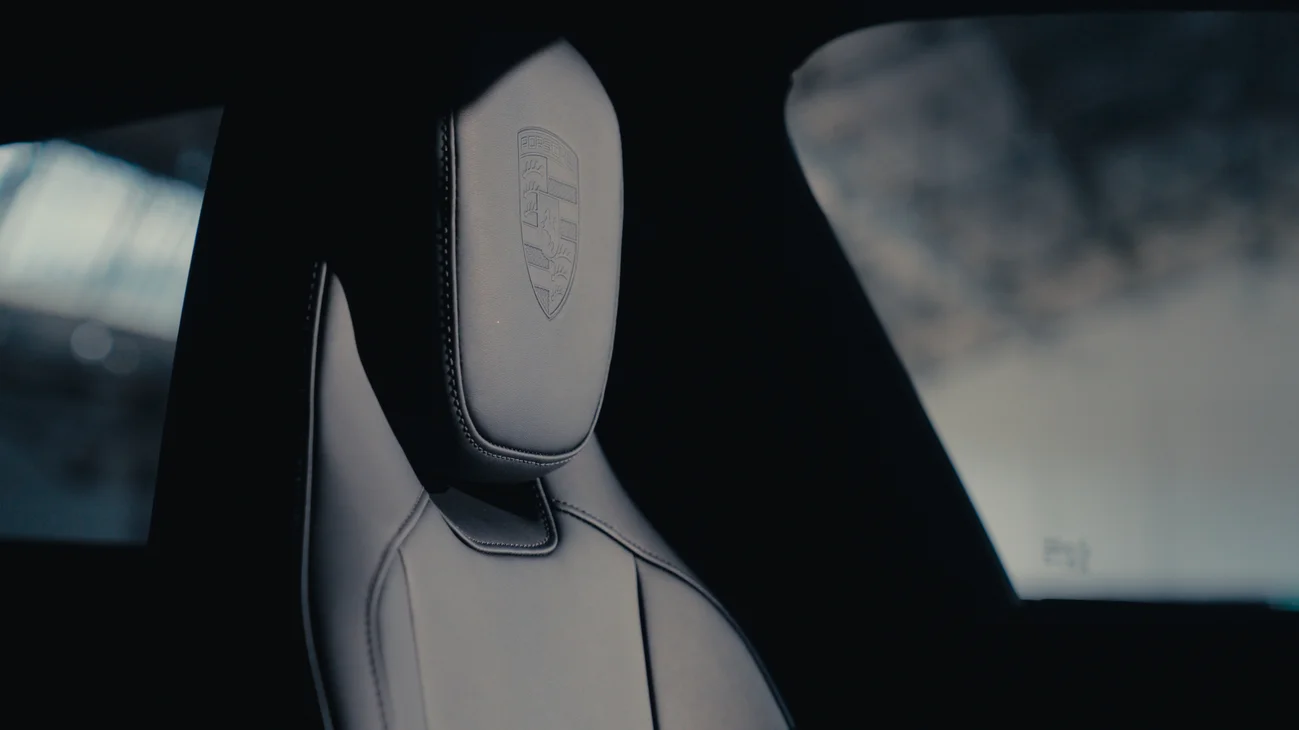 Close up of a car seat with a Porsche crest on the headrest.