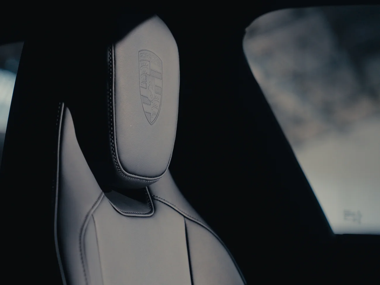 Close up of a car seat with a Porsche crest on the headrest.