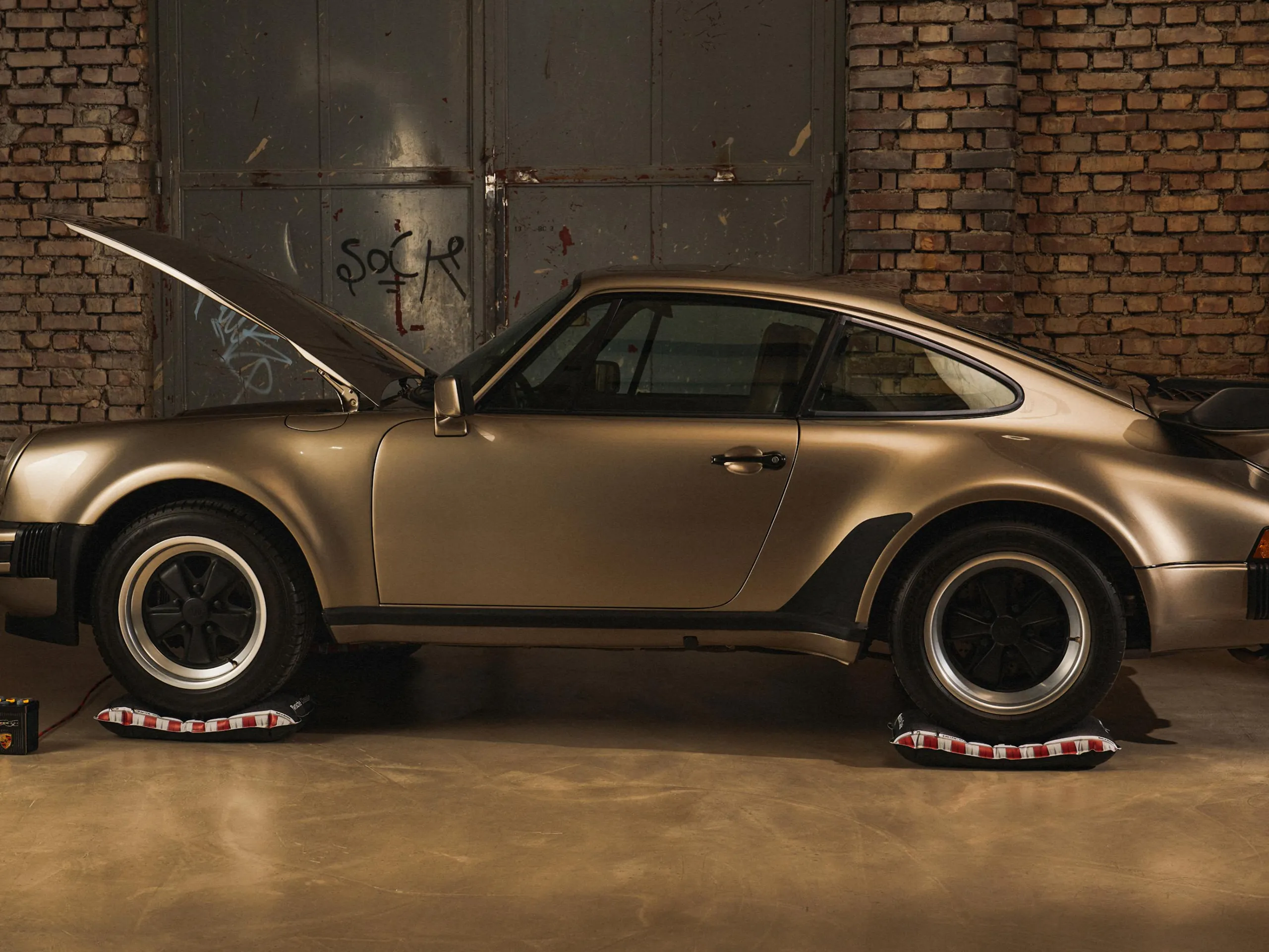 A classic Porsche stands on tire protectors with hood open in a garage; text reads “Porsche Seasonal Change”.