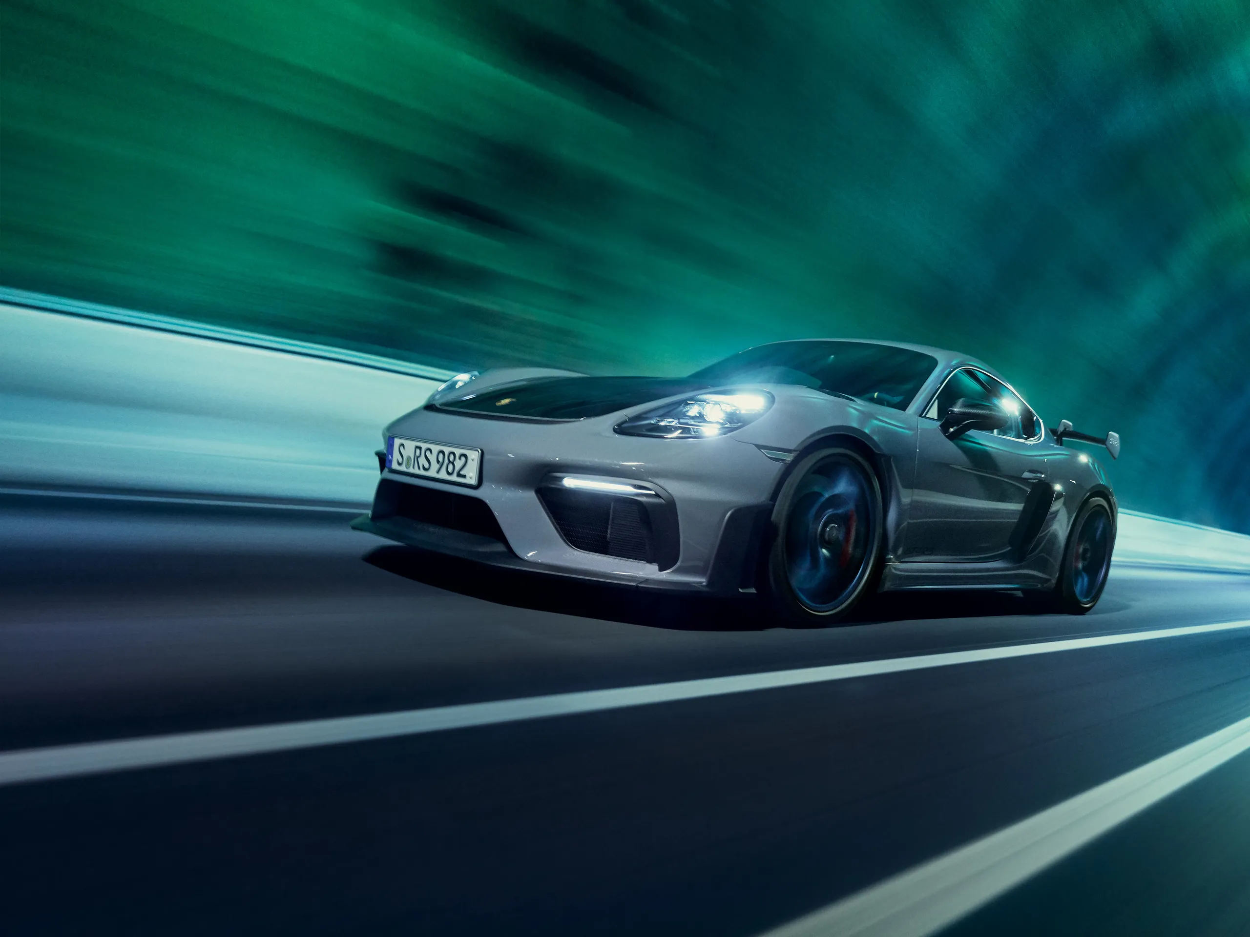 Front shot of a gray 718 GT4 RS driving through a colorfully lit tunnel in the Faroe Islands.