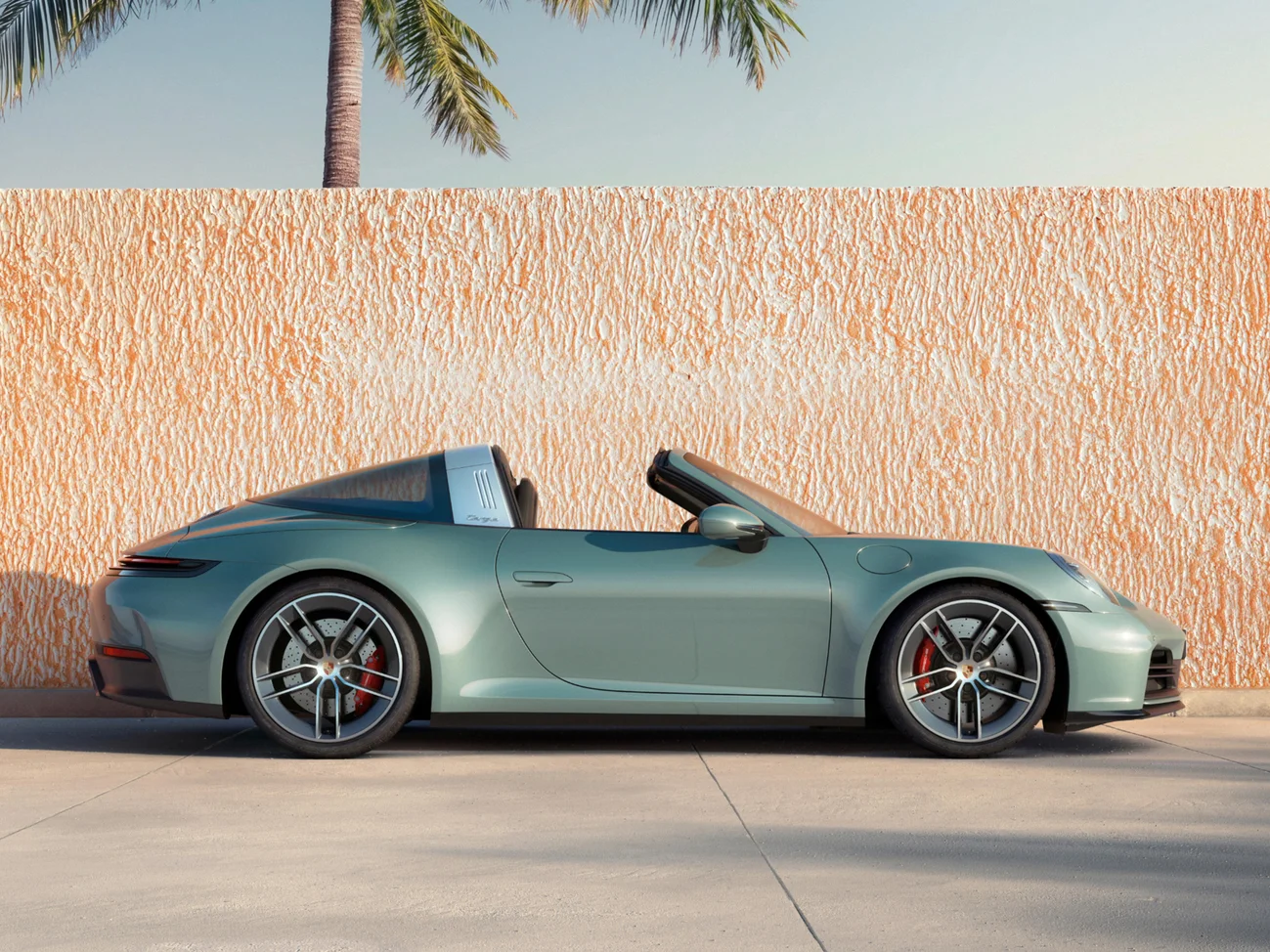 Side shot of shade green metallic 911 Targa 4S in front of orange low wall.