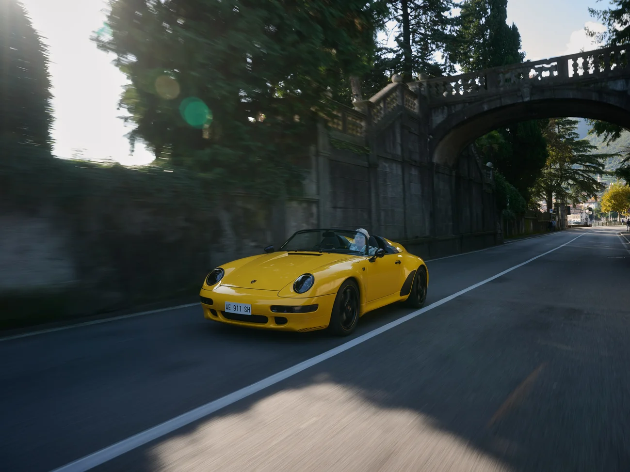A yellow Porsche driving down the road.