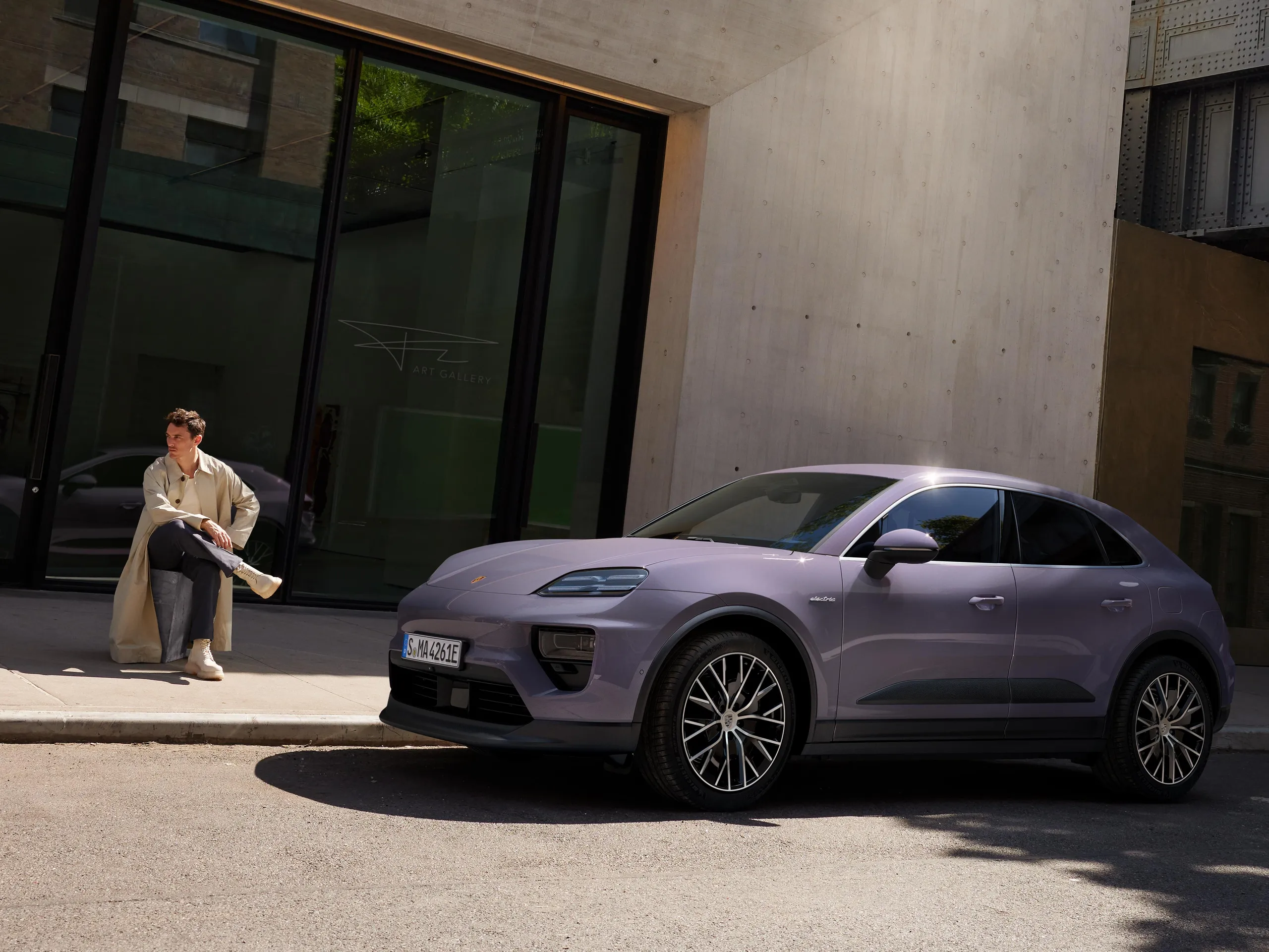 A provence Macan 4 parked on a street in front of a modern building.