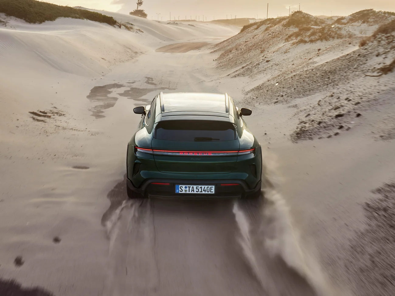 Several dynamic shots of an oakgreenmetallic neo colored Taycan Turbo Cross Turismo driving through the desert.