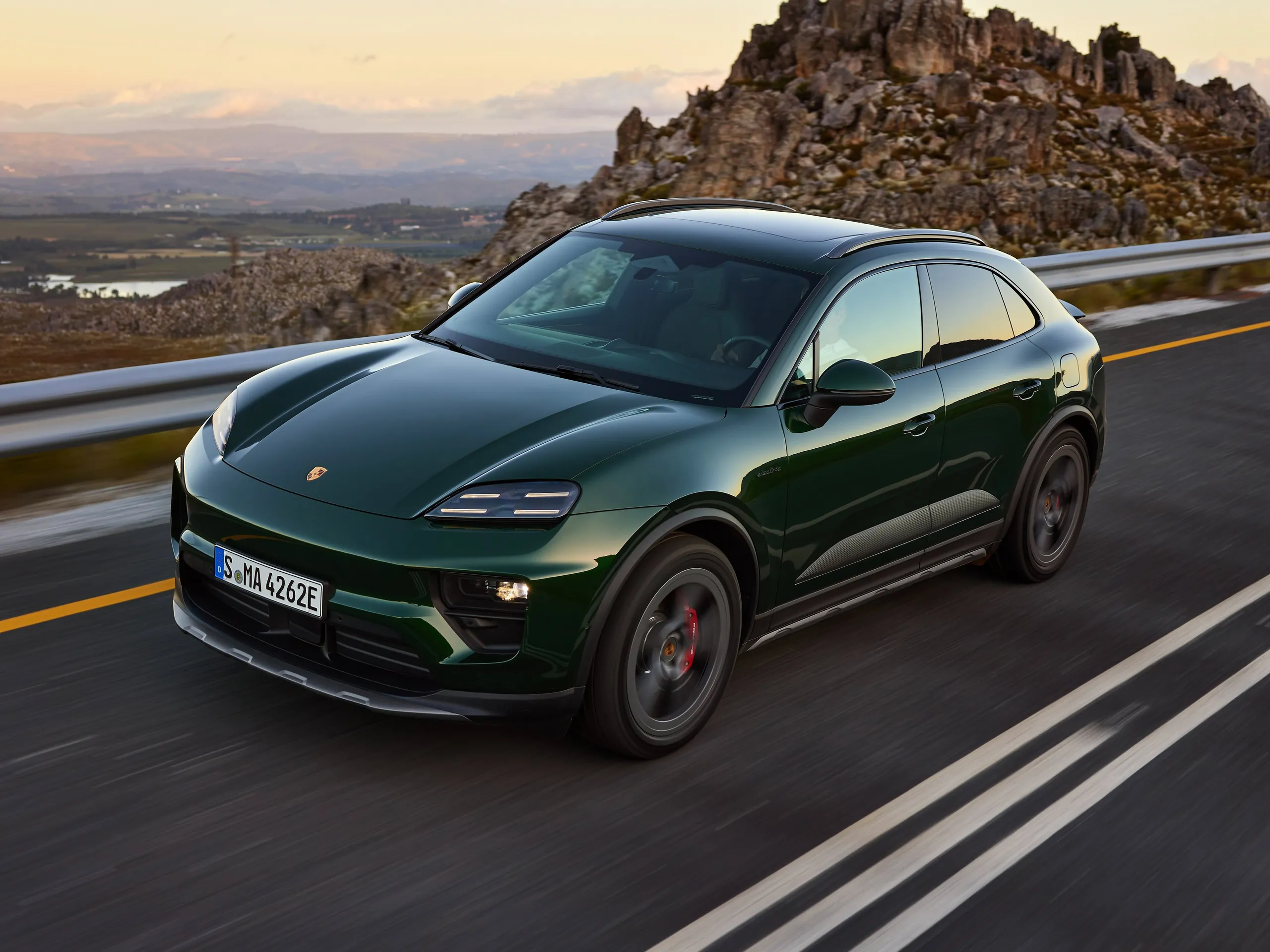 Oak green Macan 4S driving at dusk.