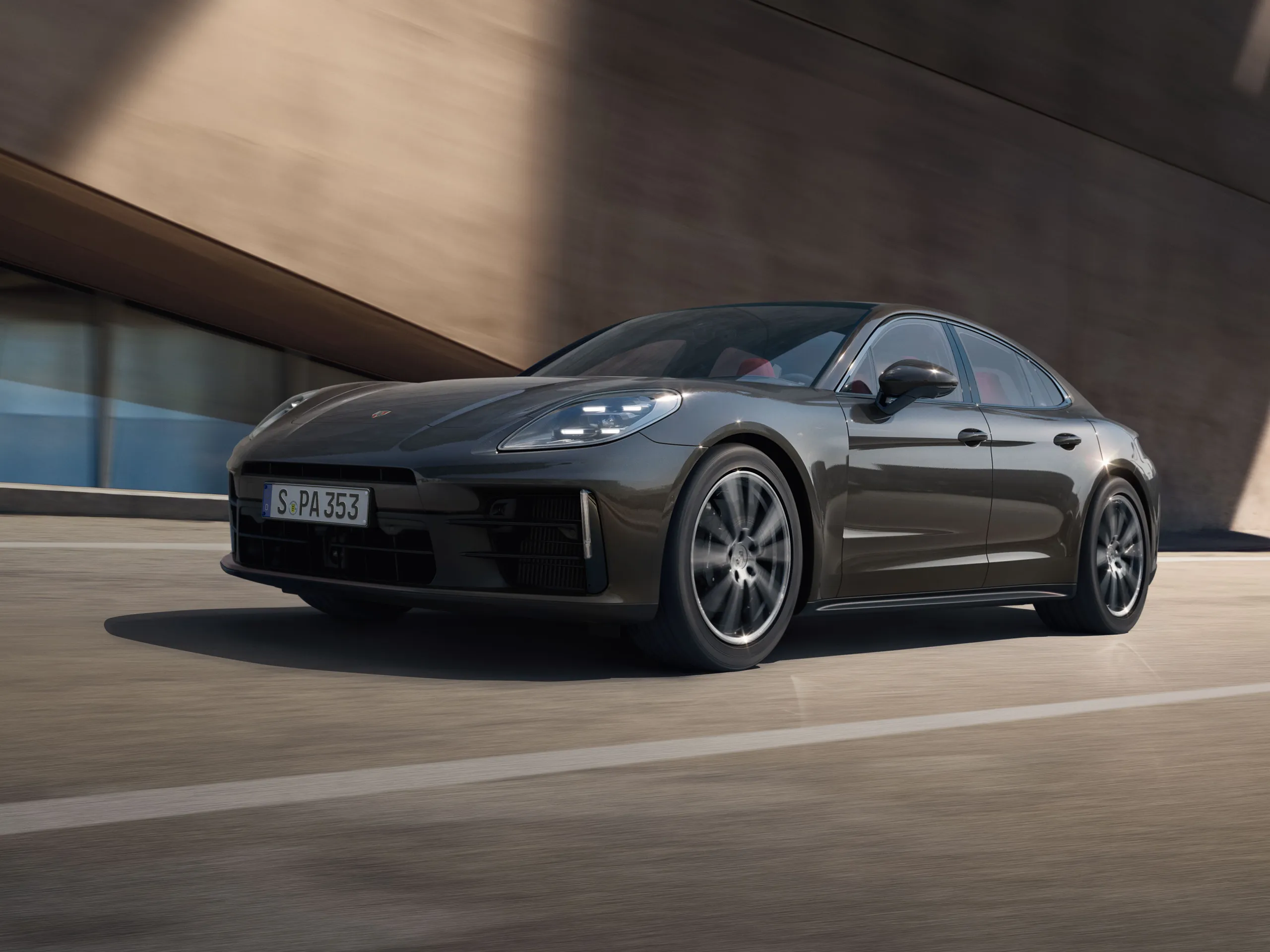Front shot of the new Panamera 4  in grey drivingon the road next to modern buildings.