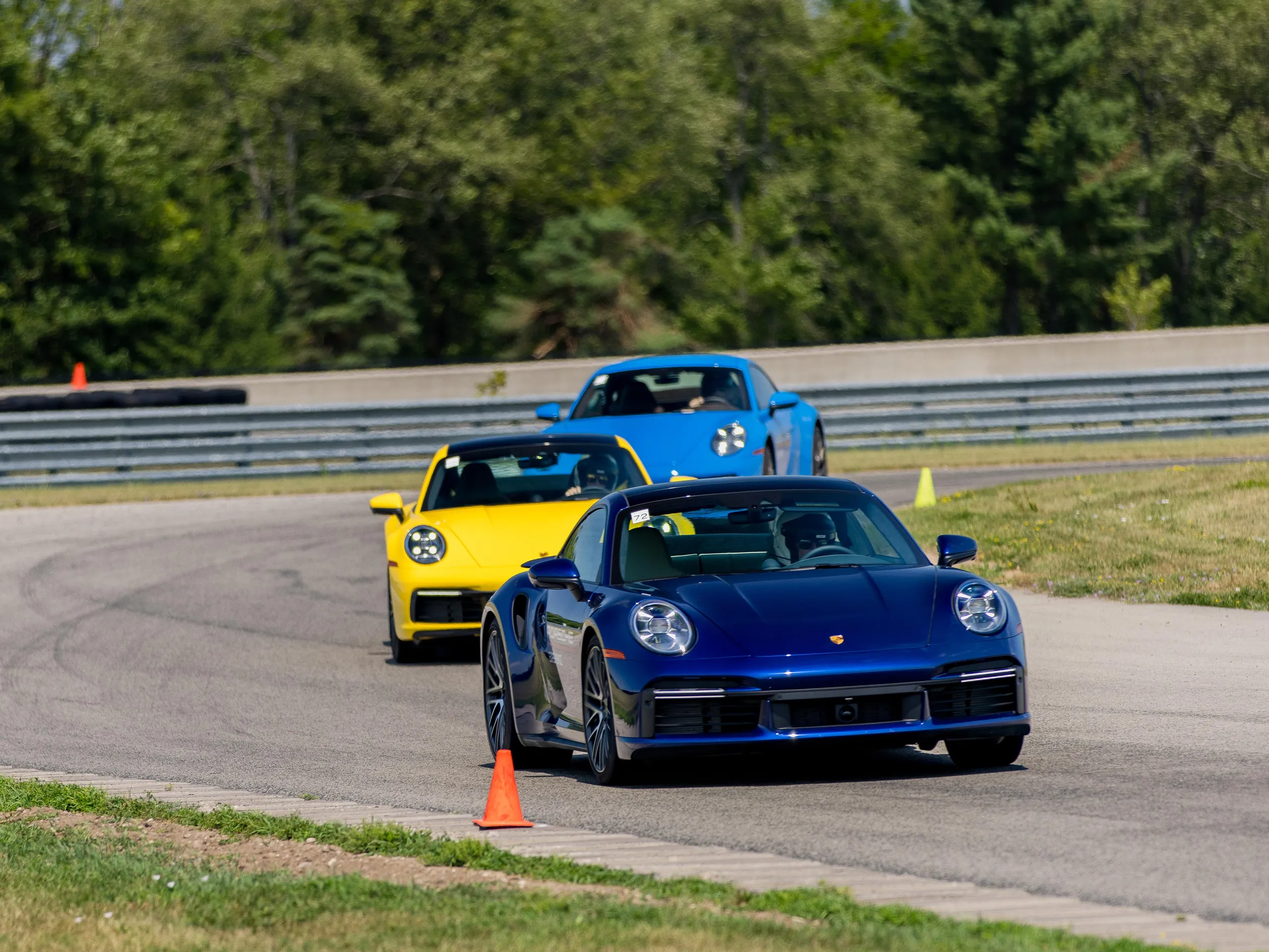 Three Porsche 911s rounding a corner on a track.
