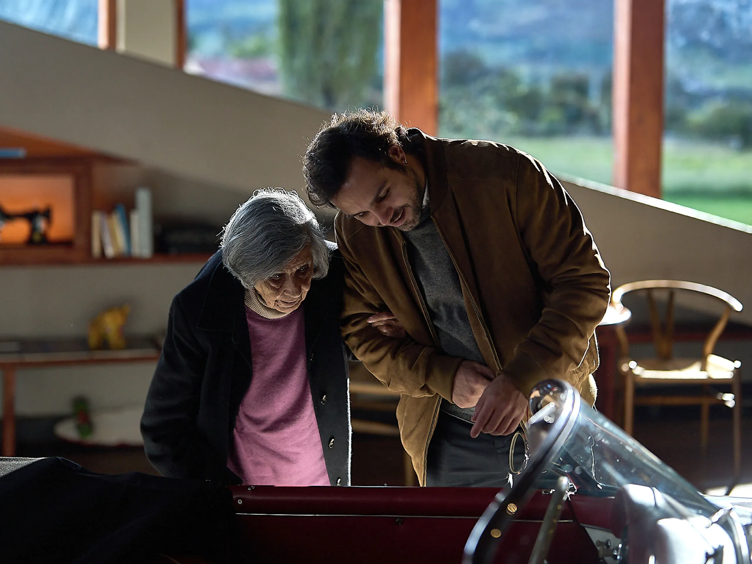 Two people look at a Porsche classic car. 