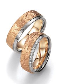 Zwei Eheringe aus Gold und Silber; einer mit strukturierter Oberfläche, der andere mit eingefassten Diamanten. Beide bestechen durch ihren einzigartigen zweifarbigen Stil.