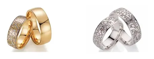 Zwei Sätze Eheringe: einer aus Gold mit aufwendigen Mustern, der andere aus Silber mit floralen Gravuren, präsentiert auf weißem Hintergrund.