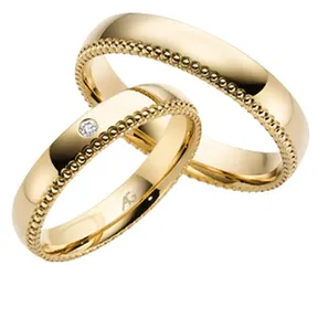 Trauringe in Gelbgold und einem Muster außenrum der Damenring hat einen diamanten in der Mitte