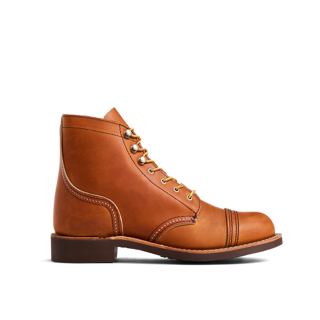 A brown leather boot with light stitching, brass eyelets, and a stacked heel against a black background.