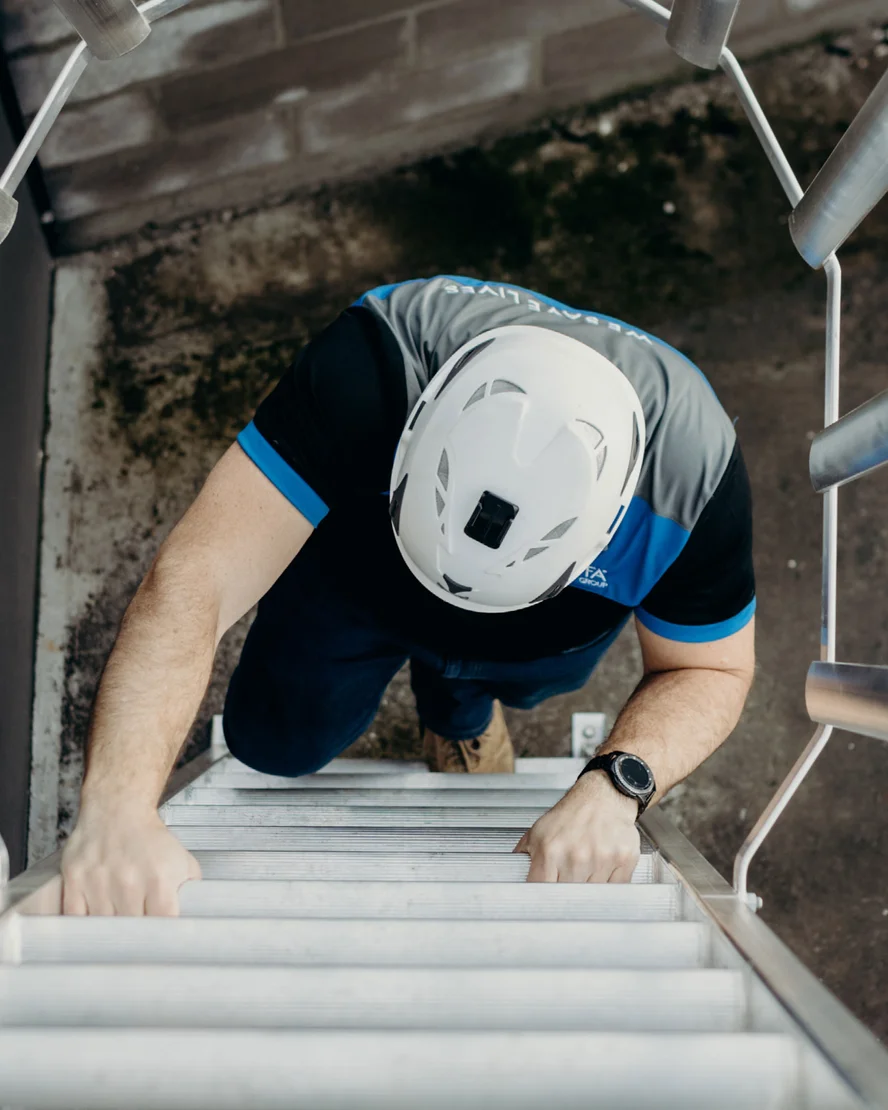 Worker in a helmet climbing a Kattsafe access ladder
