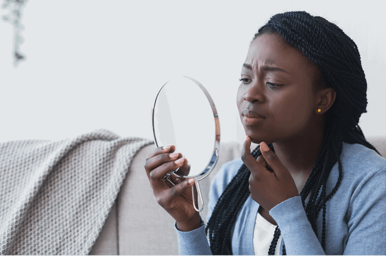 woman looking in mirror at her face