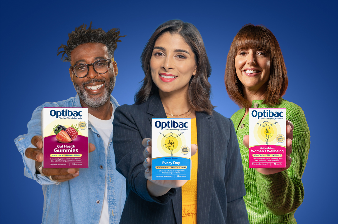 Three people smiling, each holding a different Optibac probiotic product box against a blue background.