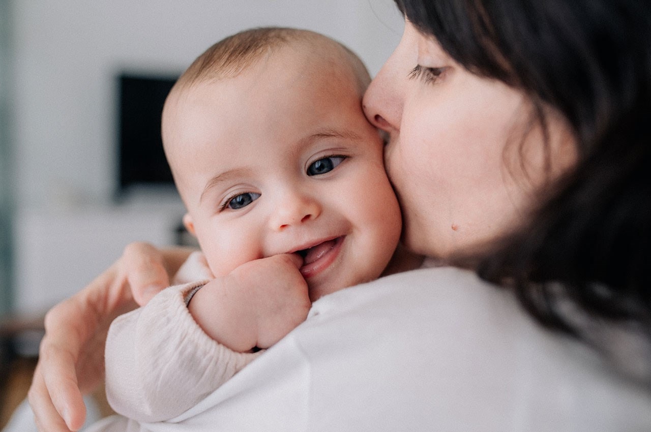 Mother kissing smiling baby