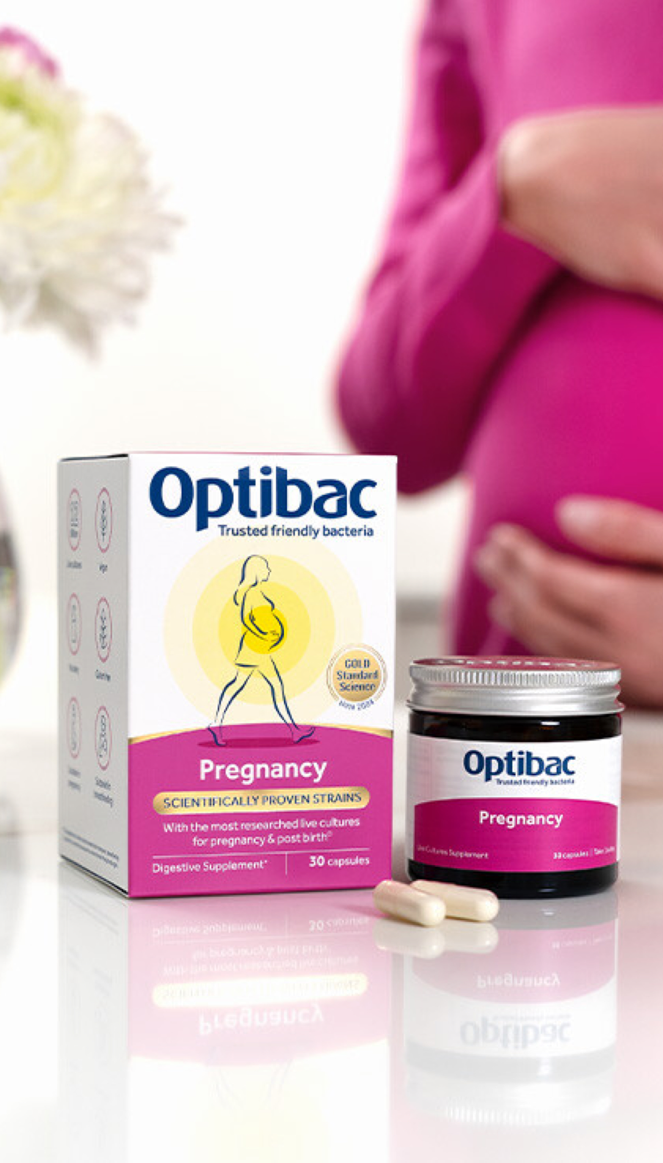 Optibac Pregnancy with packaging, a jar, and capsules. A person in pink holds their pregnant belly in the background.