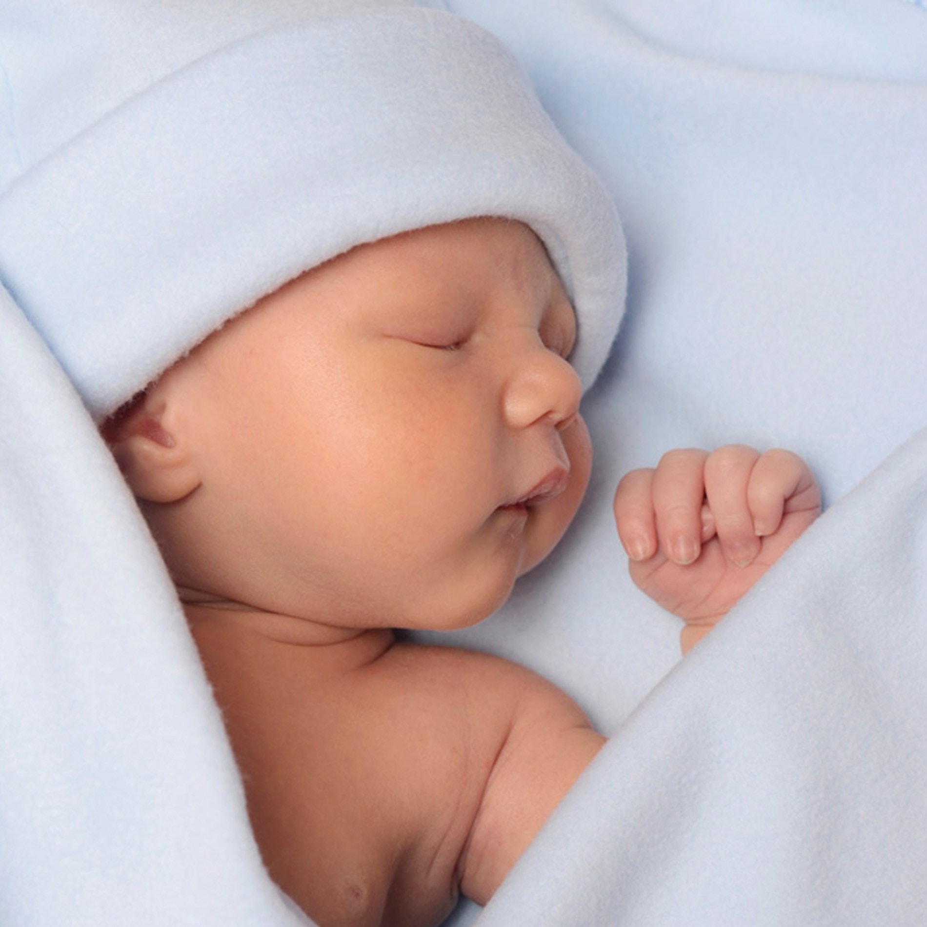 Sleeping baby wrapped in a soft blue blanket, wearing a matching hat, with a peaceful expression.