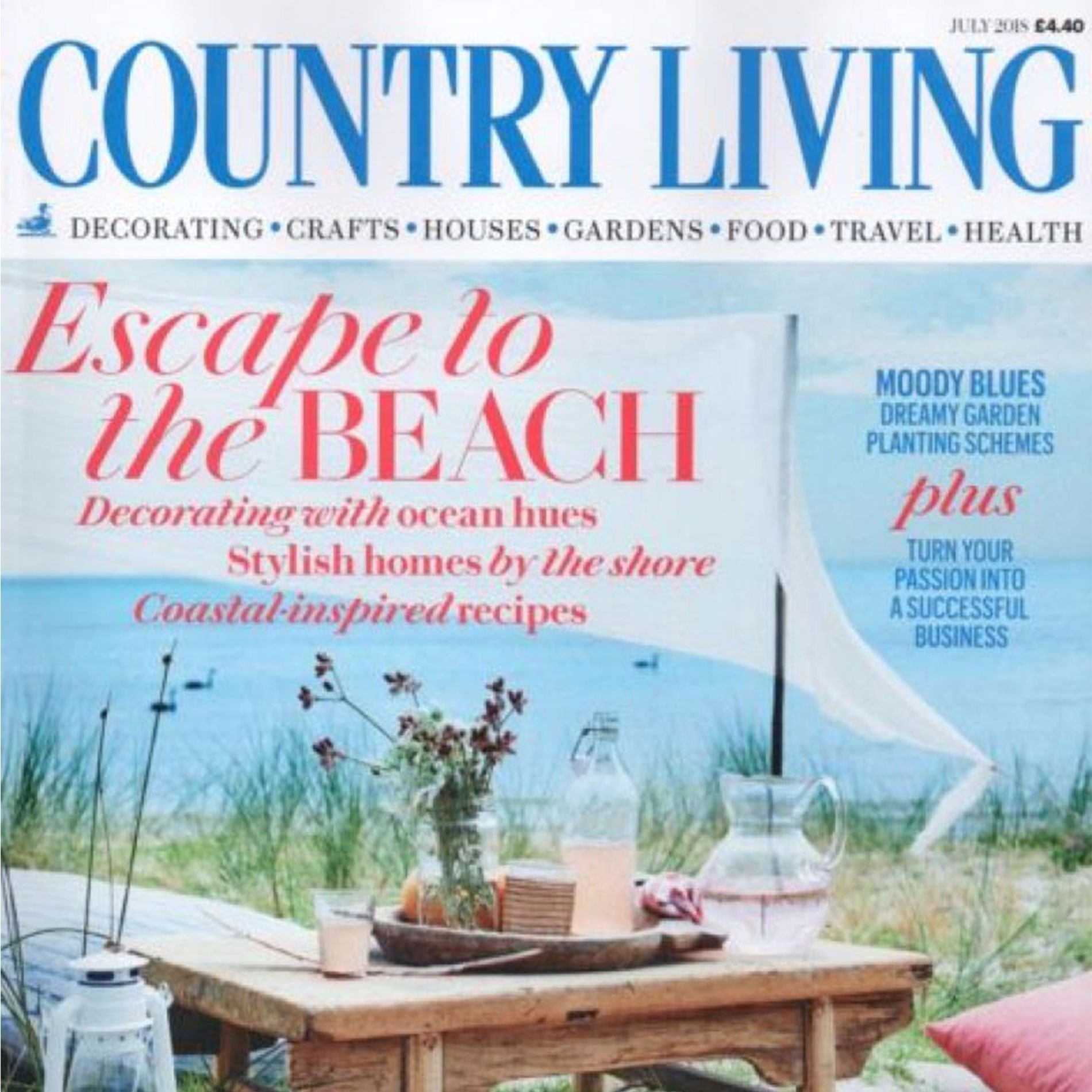 Country Living magazine cover featuring a beach scene with a wooden table, flowers, and glass bottles. Headlines about beach decor and gardening.