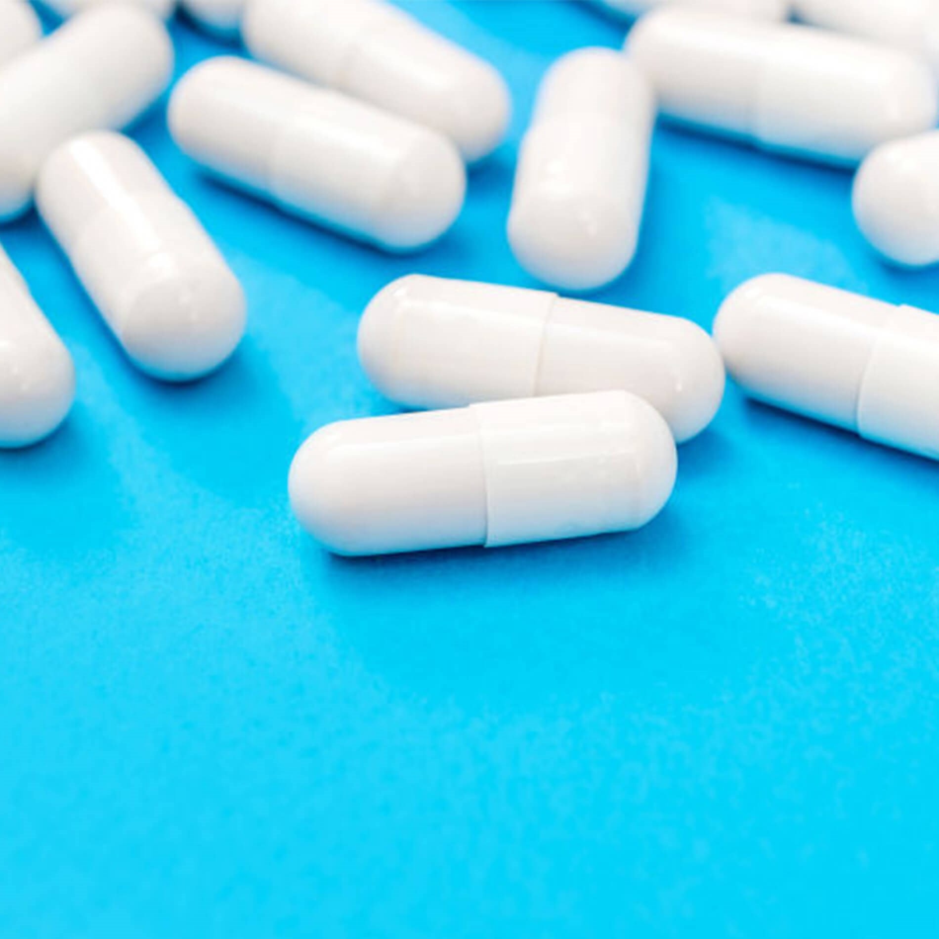 White capsules scattered on a bright blue surface.
