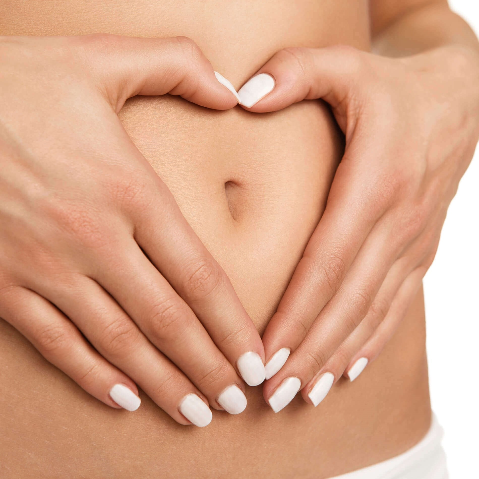 Hands with white nail polish forming a heart shape on a bare stomach, centered around the belly button.