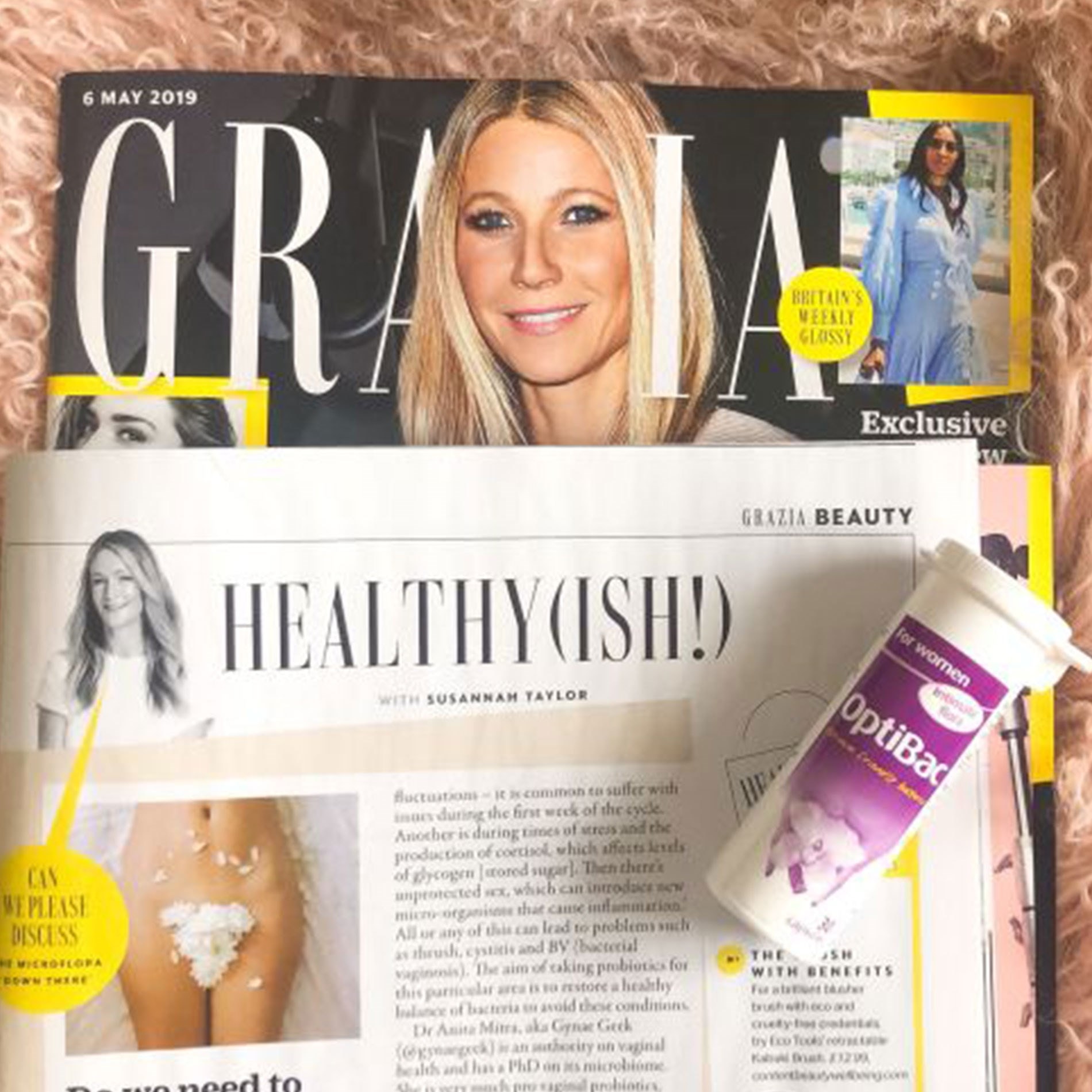 Magazine cover featuring a smiling woman, with an article titled "Healthy(ish)" and a bottle of OptiBac supplements on a pink textured surface.