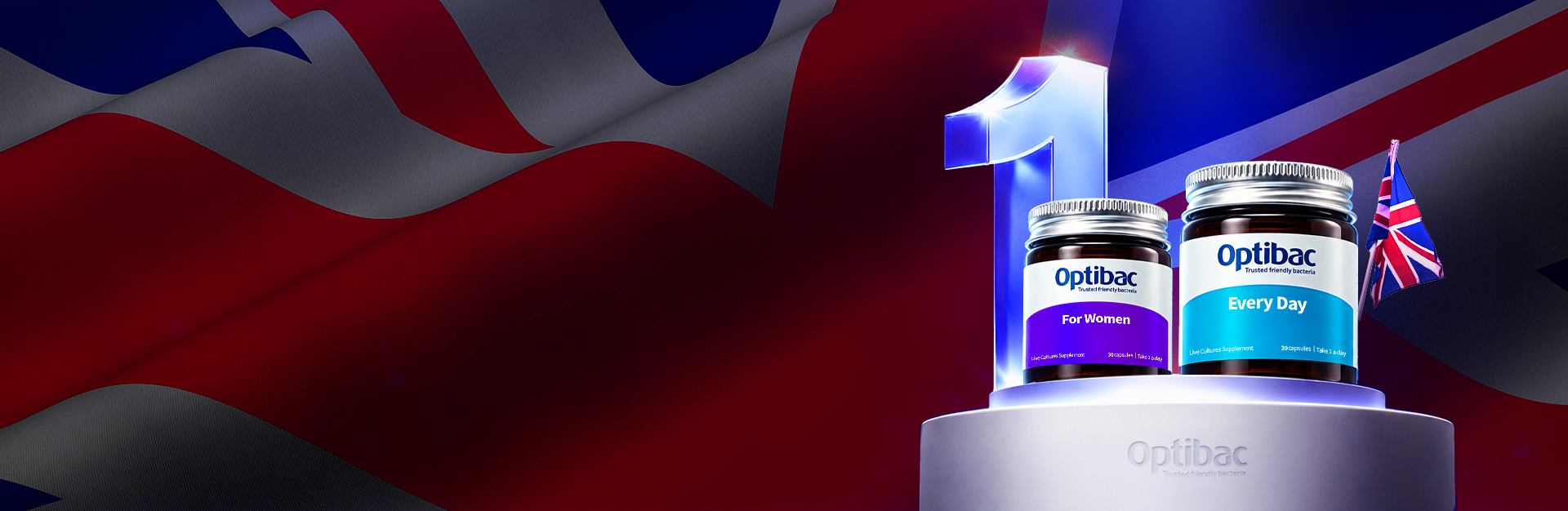 Two Optibac supplement jars, "For Women" and "Every Day," on a podium with a Union Jack, against a backdrop of the British flag.