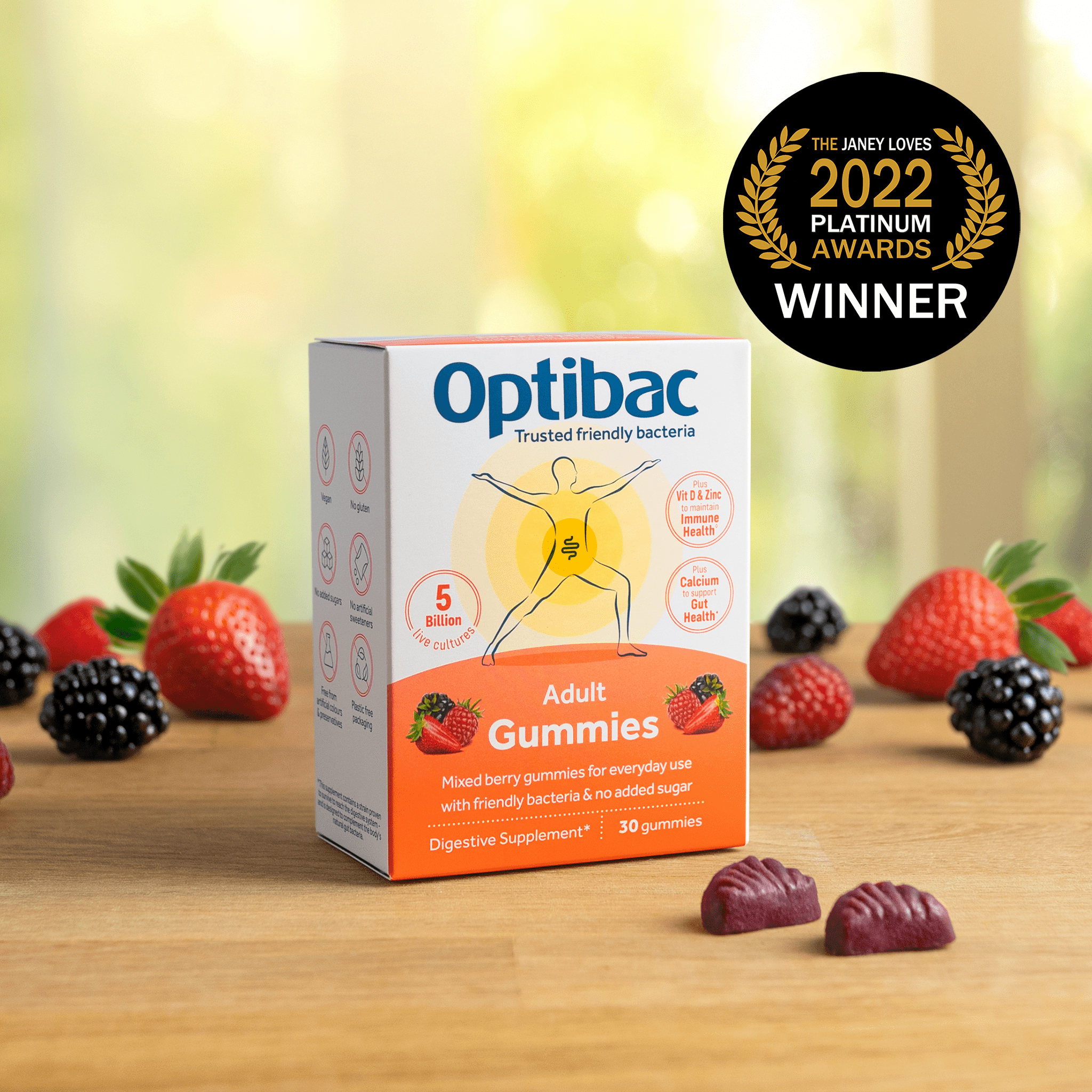 Box of Optibac Adult Gummies on a wooden surface, surrounded by assorted berries, with a "2022 Platinum Awards Winner" badge in the background.