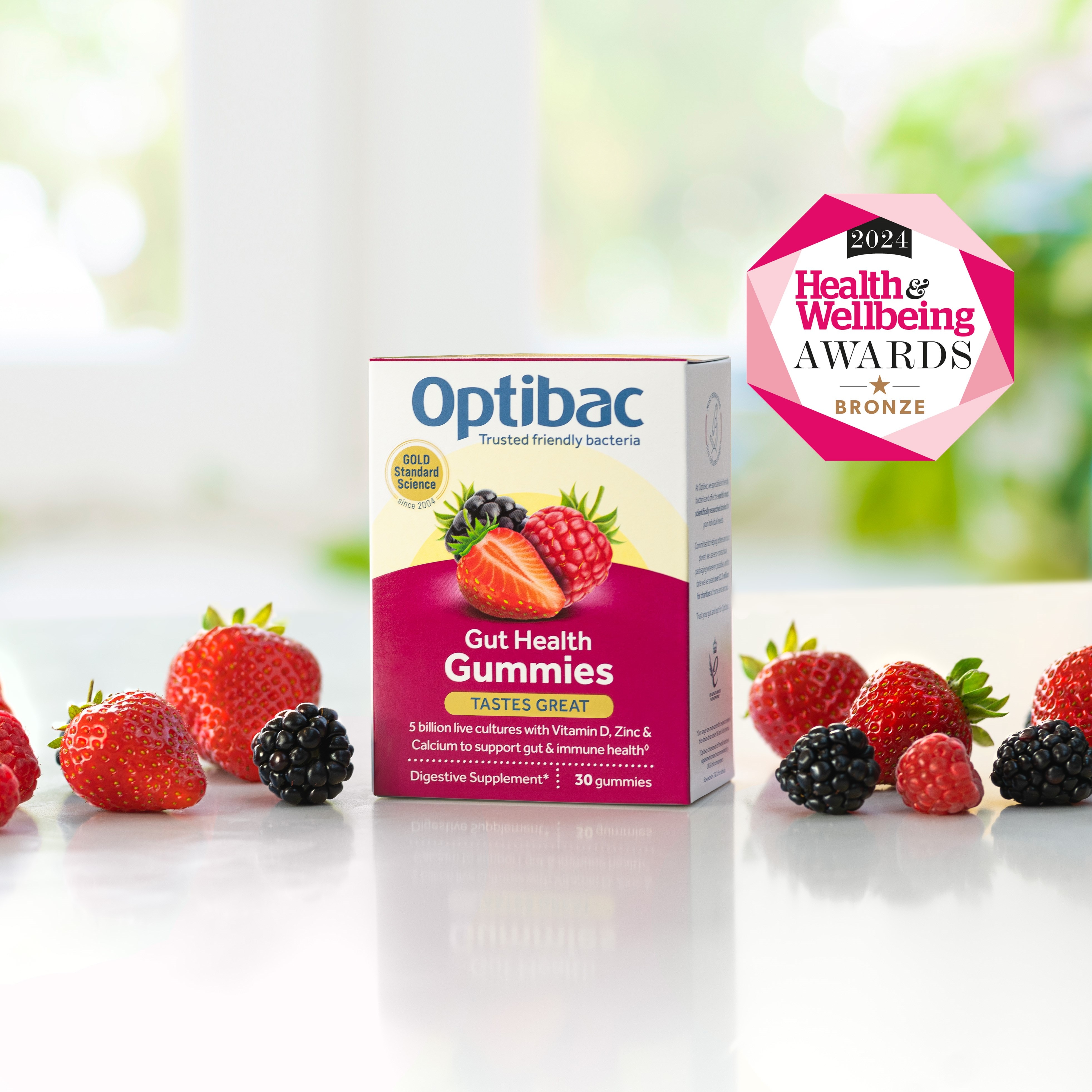 Box of Optibac Gut Health Gummies surrounded by assorted berries, with a 2021 Health & Wellbeing Awards bronze badge displayed.