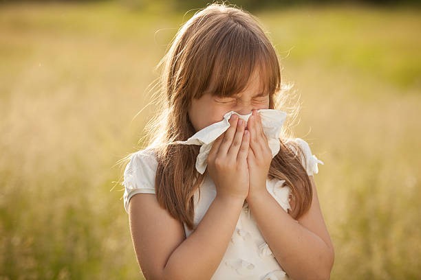 Young girl blowing her nose