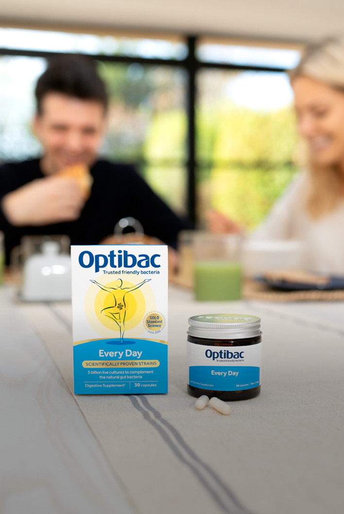 Optibac probiotic supplements on a table with two people in the background having breakfast.