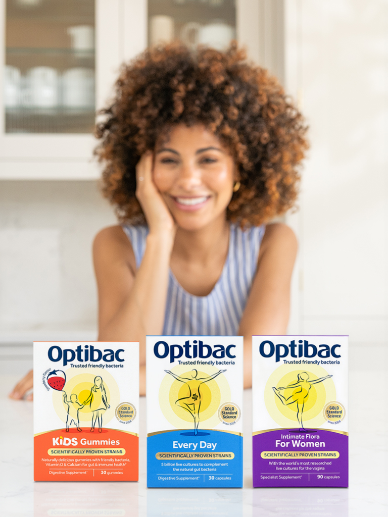 Smiling person behind three Optibac supplements: Kids Gummies, Every Day, Intimate Flora for Women, displayed on a white surface.