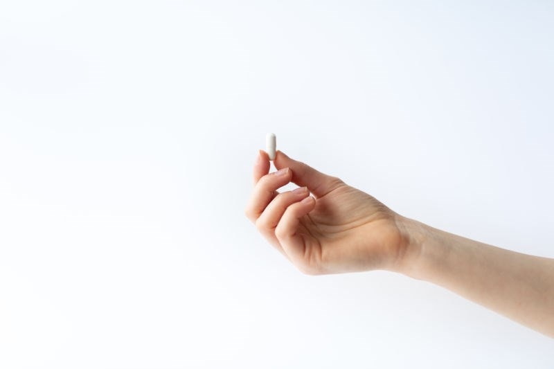 hand holding up a supplement capsule 