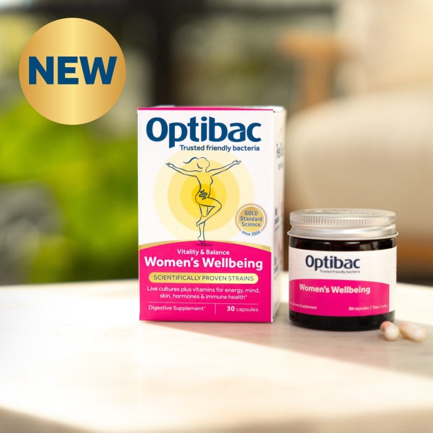 Optibac Women's Wellbeing supplements on a table, featuring a box and a jar. The box highlights scientifically proven strains and vitamins.