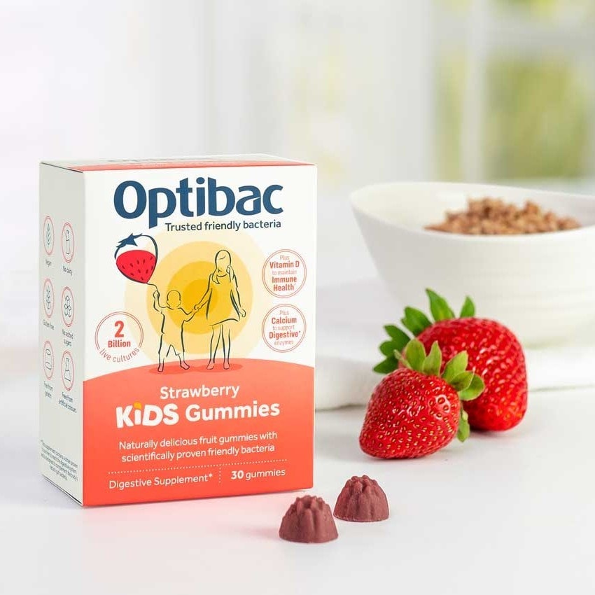 Box of Optibac Kids Gummies with strawberries and a bowl in the background. The packaging highlights digestive benefits and contains 30 gummies.