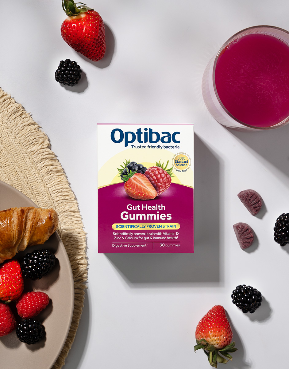 Optibac Gut Health Gummies on a table with berries, a croissant, a drink, and a woven placemat.