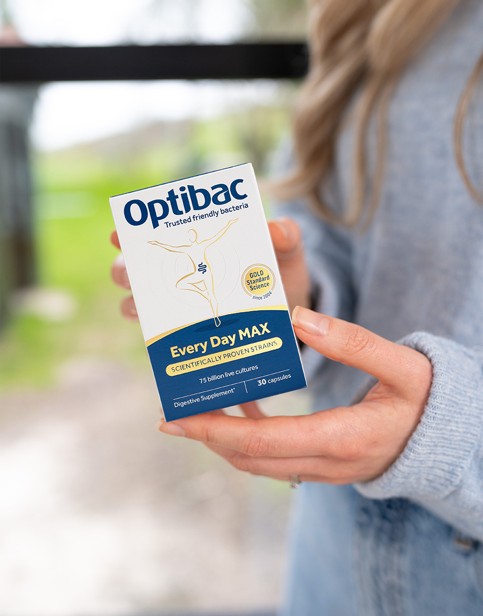 Person holding a box of Optibac Every Day MAX probiotics, featuring 75 billion live cultures per capsule.