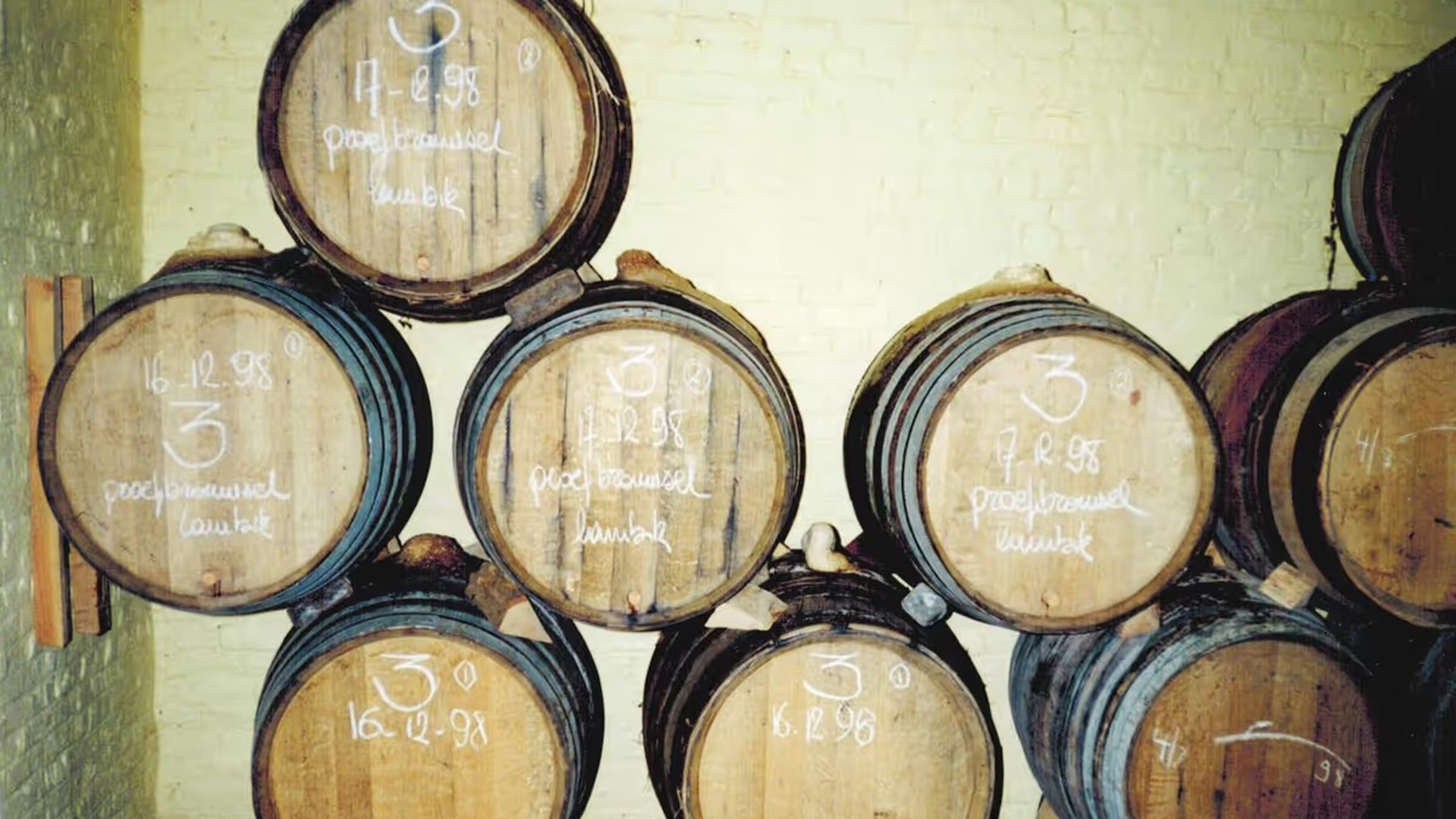 An archival shot of wooden barrels stacked two high in the old, low-ceilinged cellar.