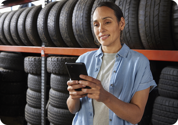 A woman looking at her phone in a tire shop.