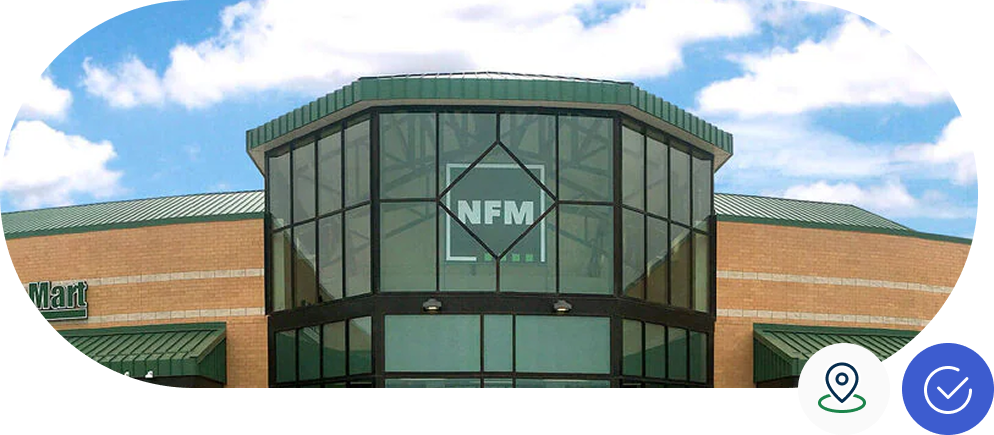 Building with a glass entrance displaying "NFM" against a clear blue sky. A brick structure with green roofing surrounds the entrance.