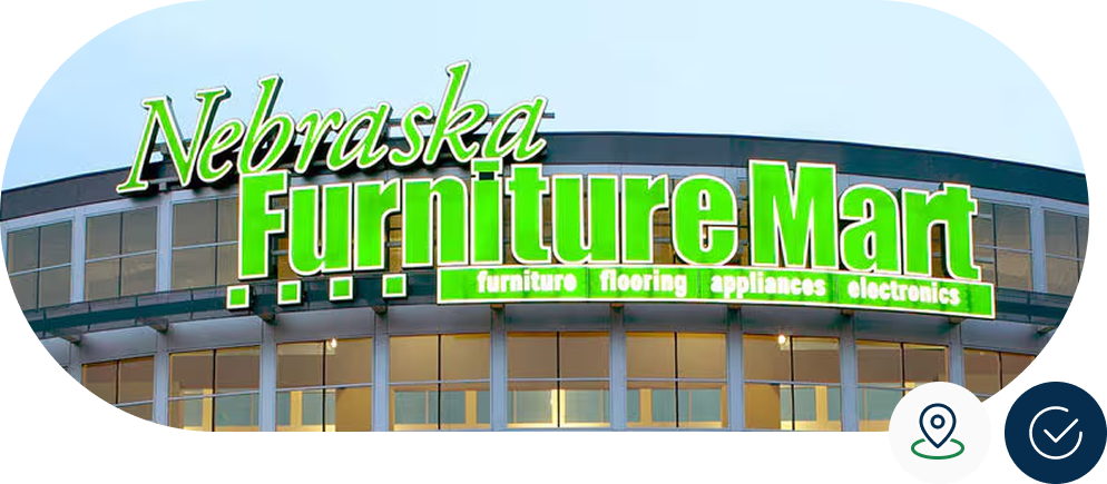 Sign on the exterior of Nebraska Furniture Mart, advertising furniture, flooring, appliances, and electronics in bright green letters.