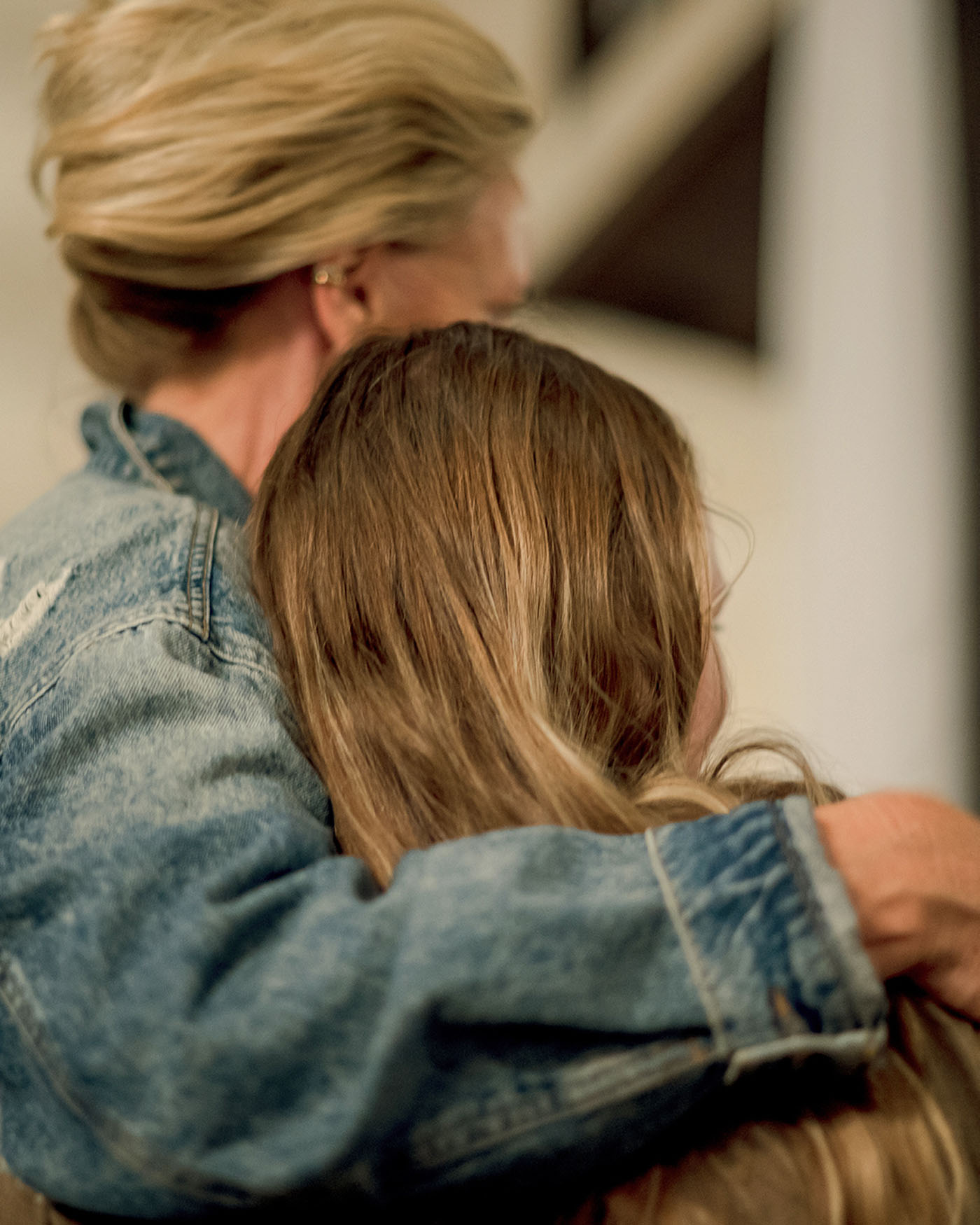 Two women stand close together, one with her arm around the other's shoulders.