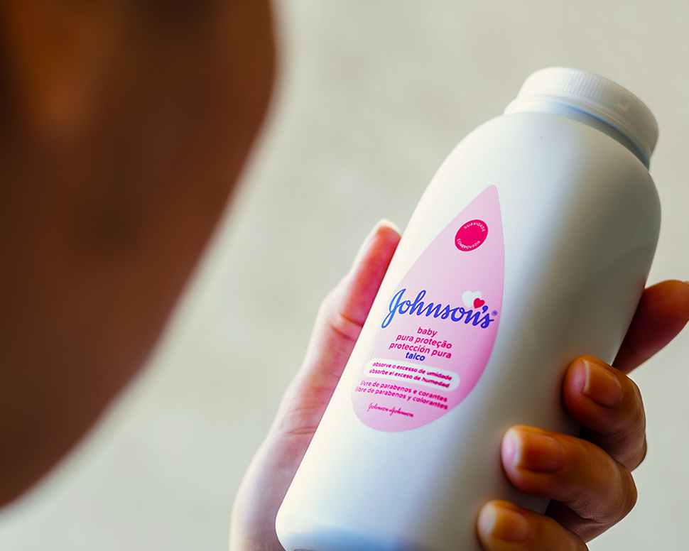 Person holding a bottle of Johnson's baby powder with a pink label.
