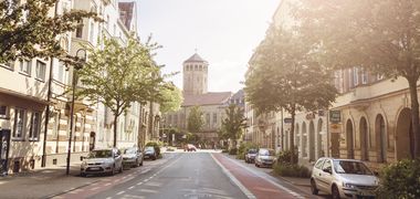 Blick in eine Straße mit Radwegen seitlich, am Ende ist ein Turm zu sehen – Wölfelstraße in Bayreuth.