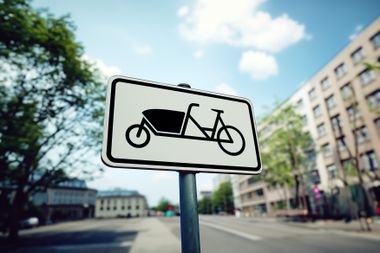 Parkplatzschild für Lastenräder, eine urbane Straße im Hintergrund.