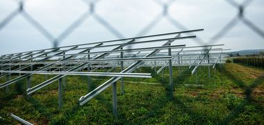 Blick durch einen Zaun auf noch leere Gerüste für einen Solarpark.