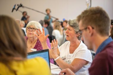 Eine ältere Frau erzählt und gestikuliert bei einer Bürgerrat Veranstaltung.